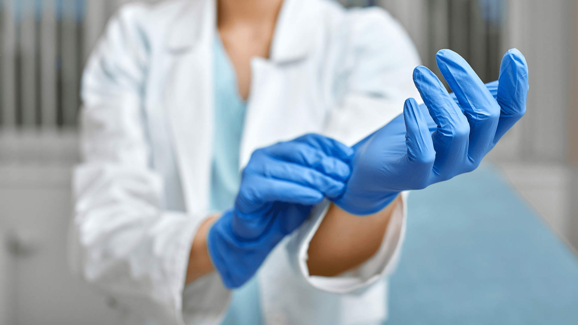 Doctor putting on blue medical gloves
